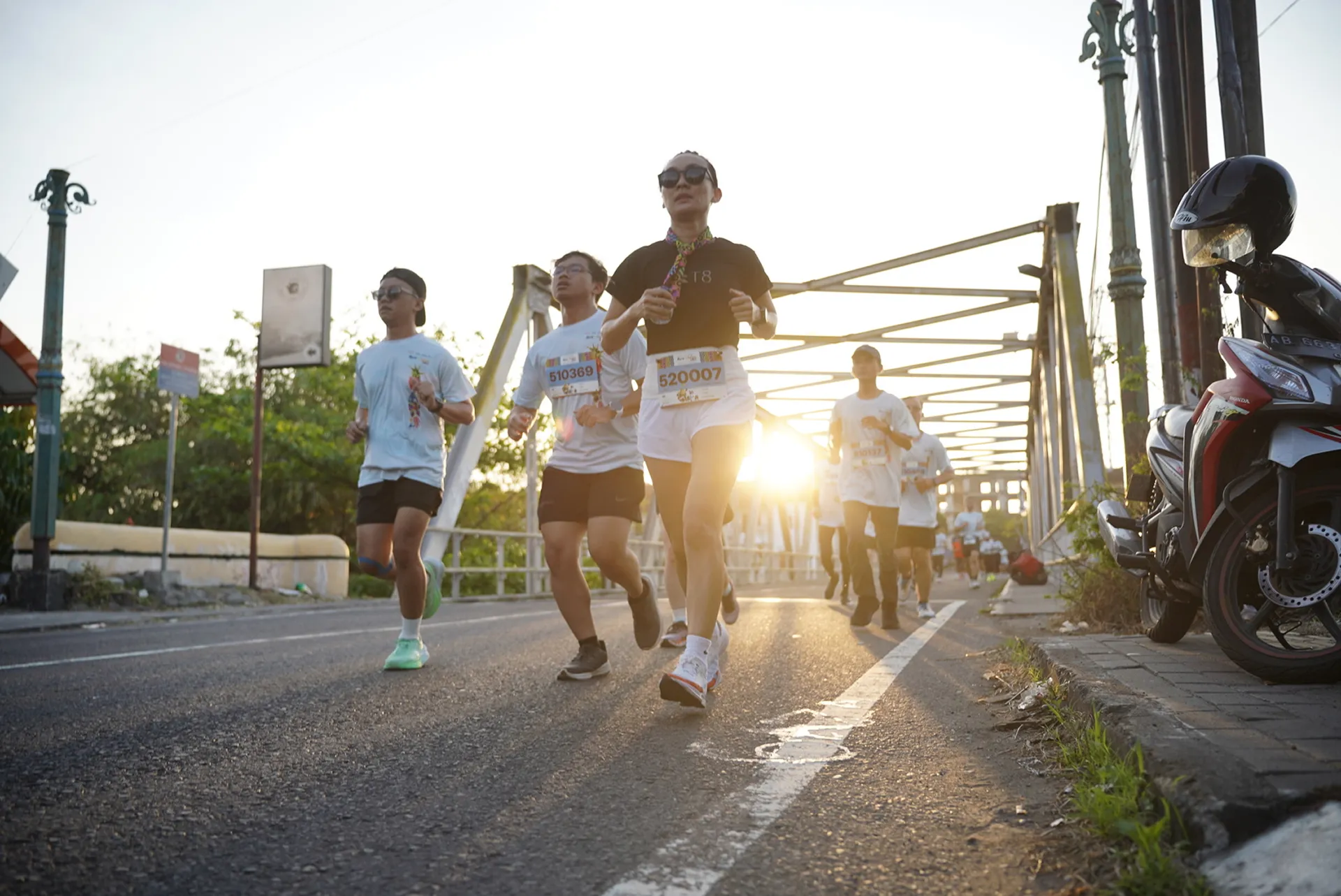 Pelari fun run Run'nShine melintasi jembatan saat golden hour di Jogja